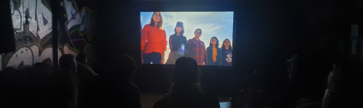 Ein Raum, in dem ein Film gezeigt und von mehreren Personen betrachtet wird
