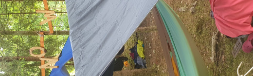 Schlafsäcke und Planen sind zwischen Bäumen zu einem Schlaflager aufgespannt