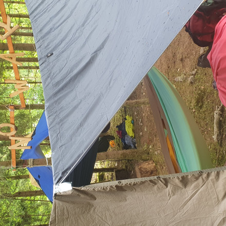 Schlafsäcke und Planen sind zwischen Bäumen zu einem Schlaflager aufgespannt